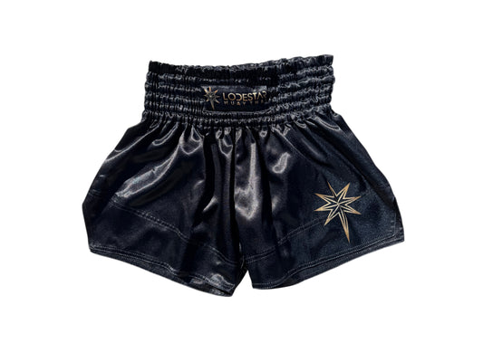 Lodestar Muay Thai black polyester shorts with elastic waistband and gold star logo. Designed for performance and comfort.