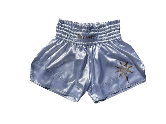 Lodestar Muay Thai shorts in light blue satin with gold star logo and elastic waistband.