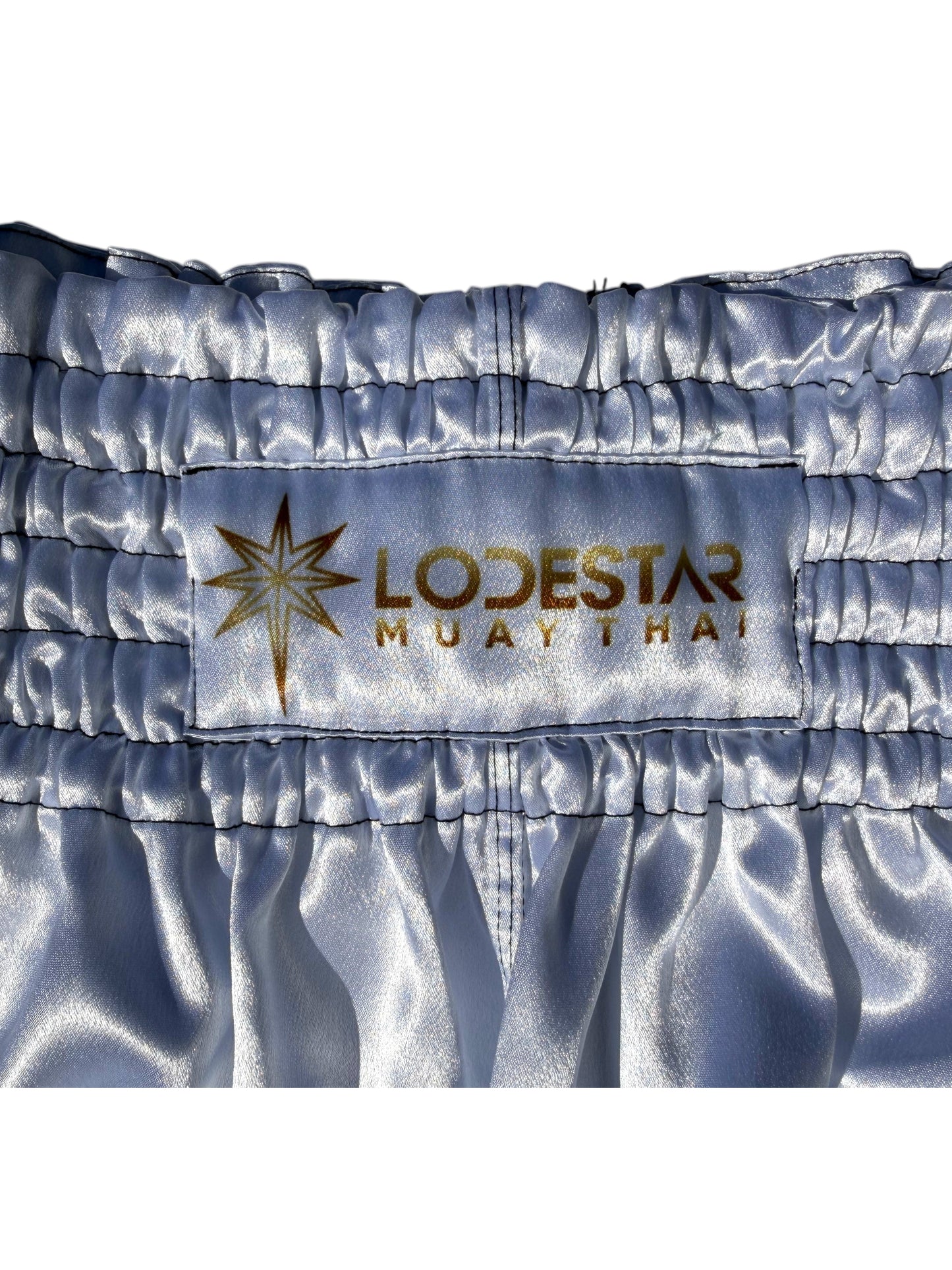 Lodestar Muay Thai shorts in light blue satin with elastic waistband and side openings for enhanced range of motion.